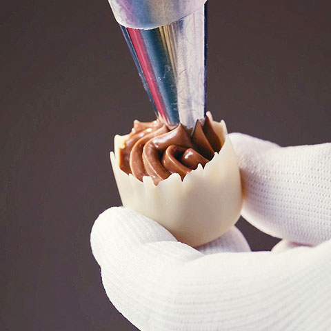 Petit-Four Schokoladenbecher wird mit Nougatcreme gefüllt